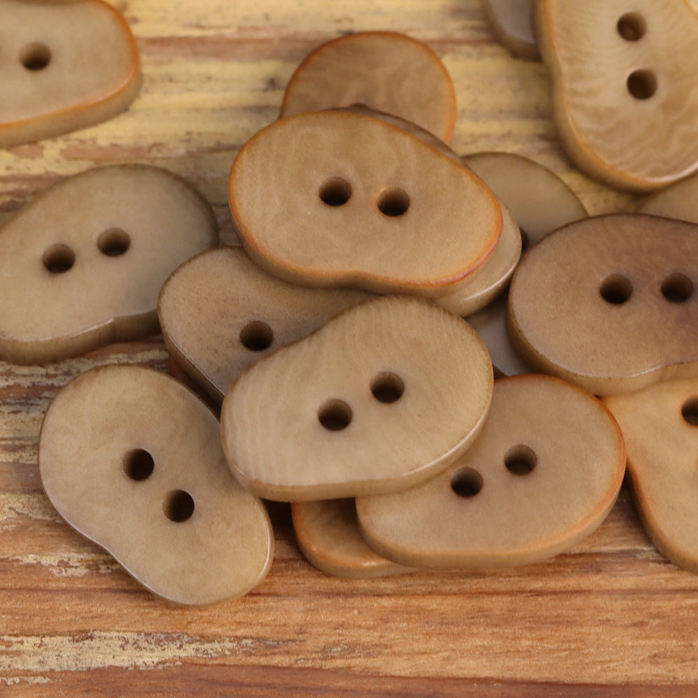 Assorted light tan peanut-shaped buttons with two holes each