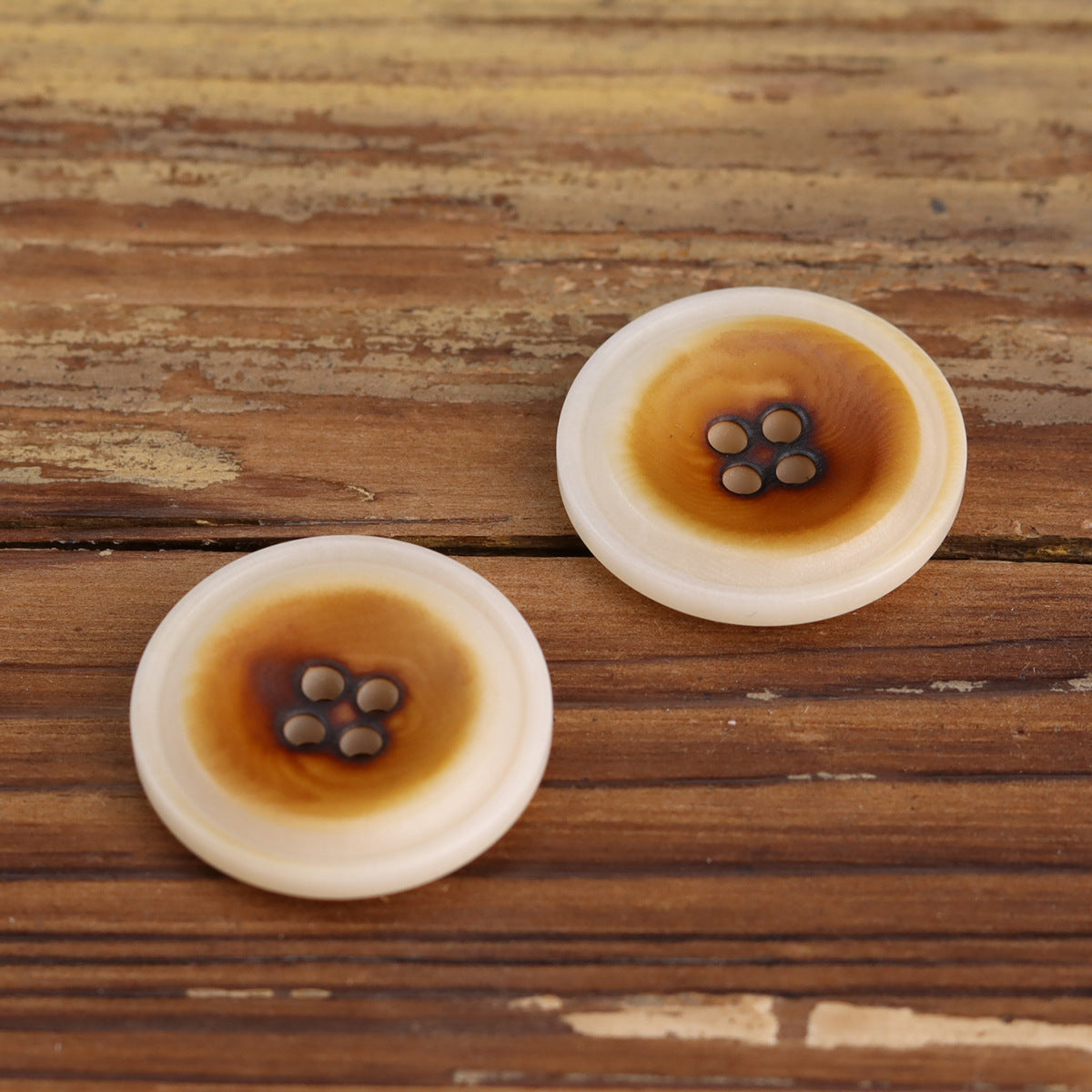 Burned white corozo buttons, two rounds showing four-hole cross arrangement