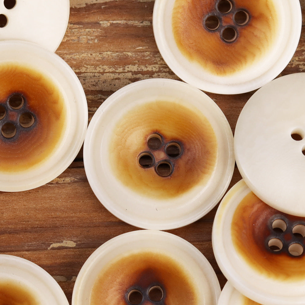 Assorted burned white corozo buttons, close-up of 4-hole shank openings