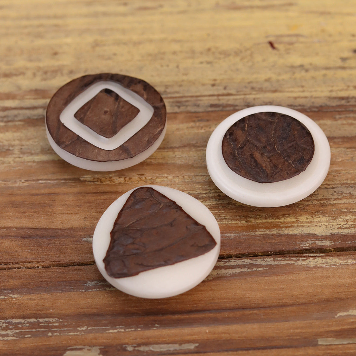 Corozo buttons in triangle and round shapes with white rims, dark brown grain
