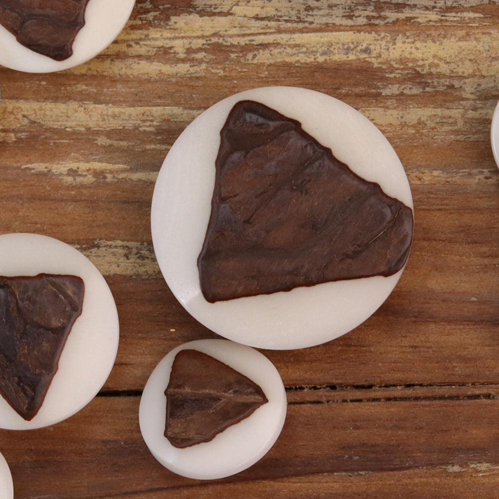 Close-up of triangular corozo button with white rim and dark brown wood grain