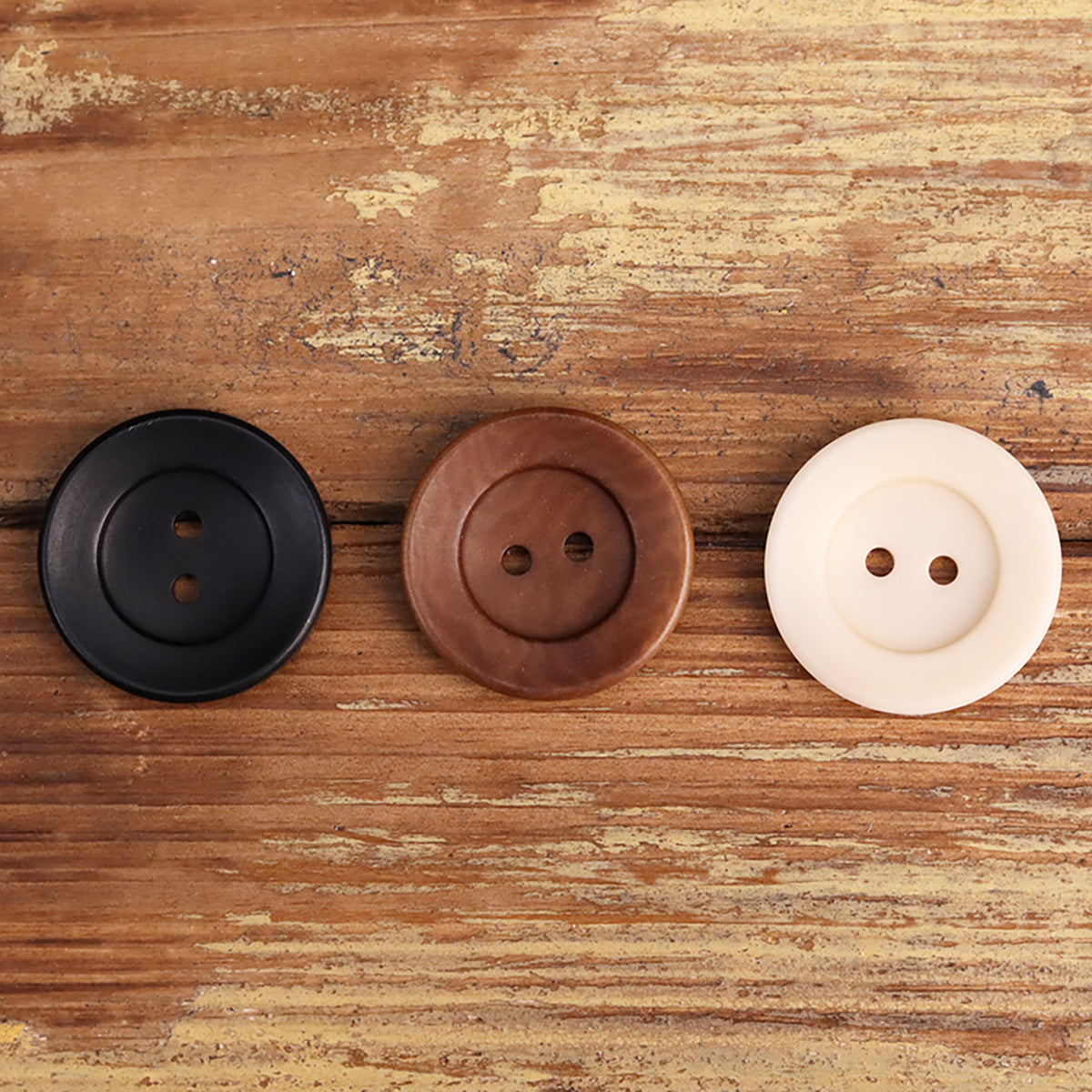 Three two-hole corozo buttons: black, reddish-brown, and white, round bowl-shaped design