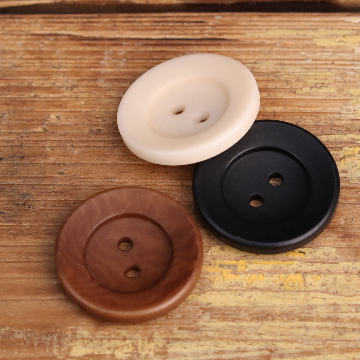 Two-hole corozo buttons in cream, black, and reddish-brown, round bowl-shaped design