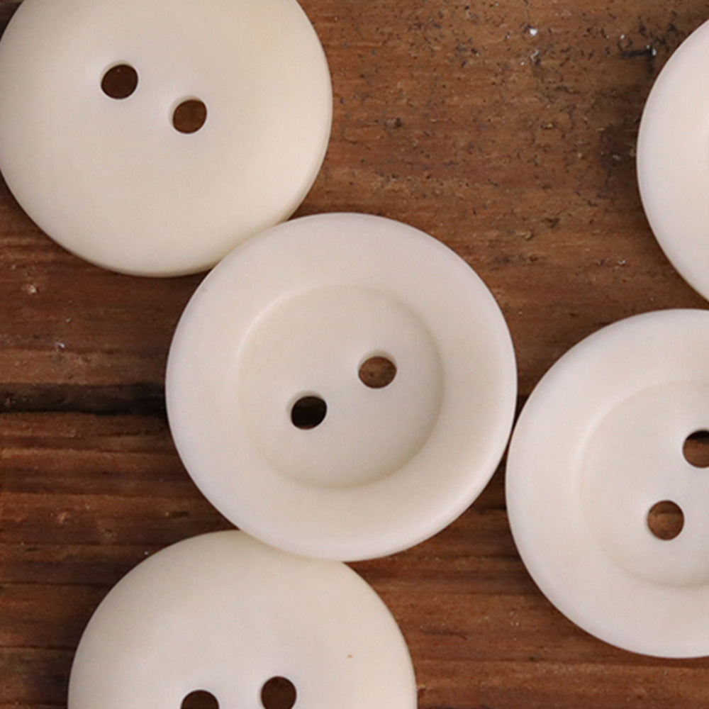 Light cream two-hole corozo buttons, round bowl-shaped, front view with two holes