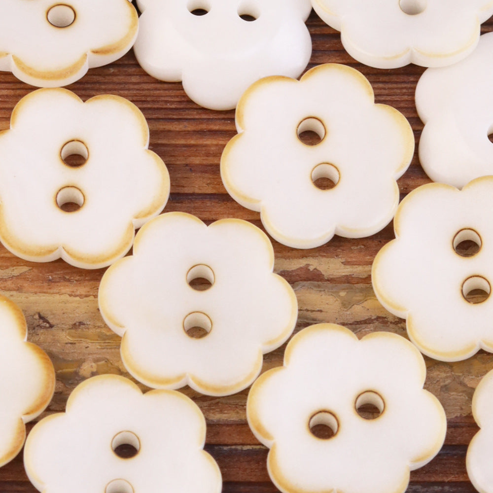 Cream flower-shaped corozo buttons with two holes, rounded petal edges.
