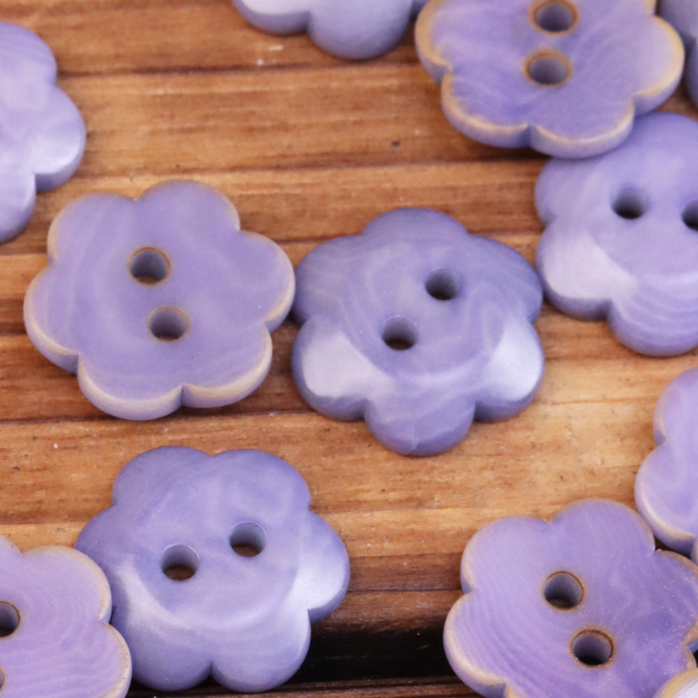 Lavender flower-shaped corozo buttons with two holes, smooth petal shape.
