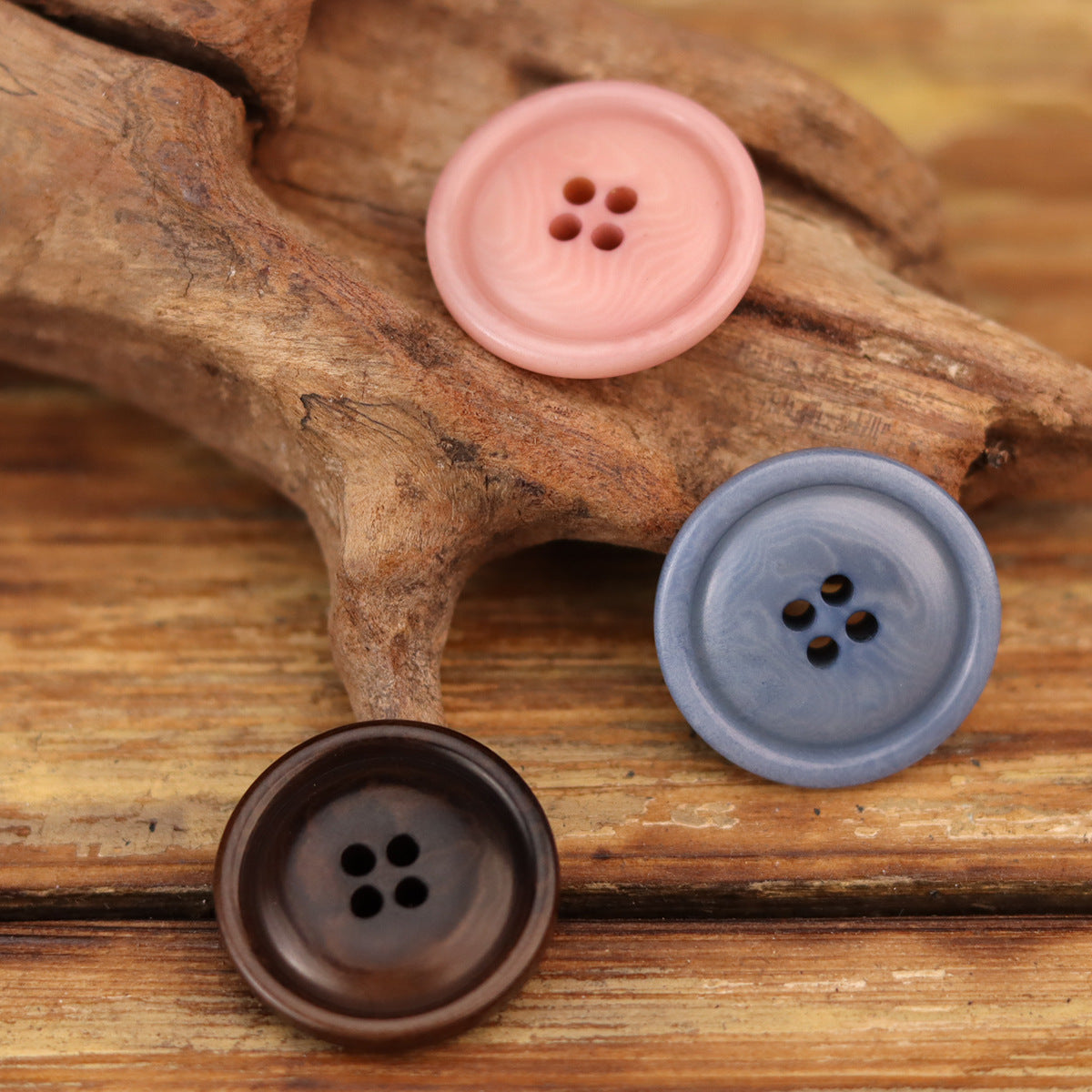 Round corozo buttons in pink, blue, and coffee with four holes