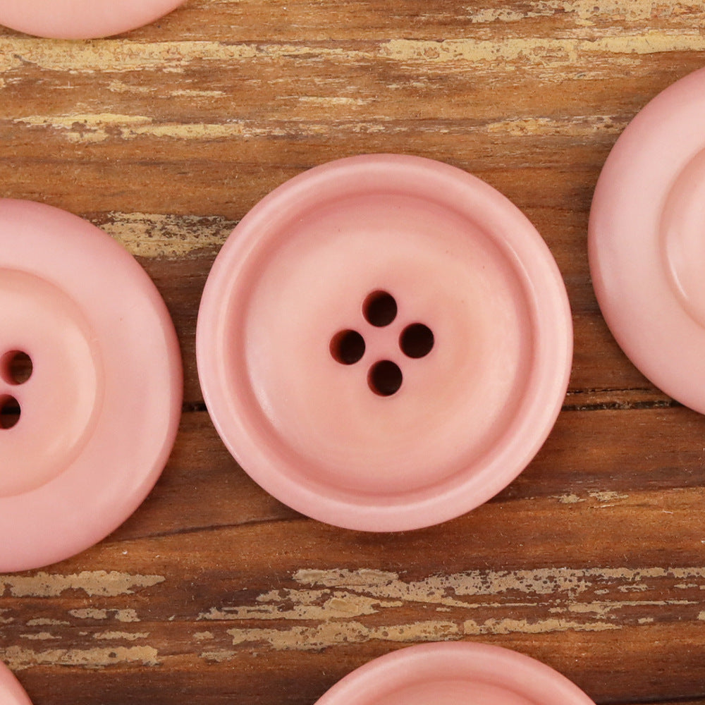 Pink corozo button close-up, round face with four holes