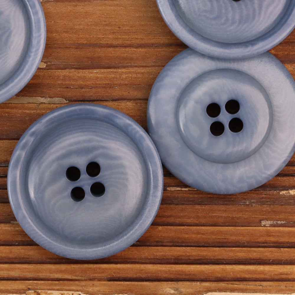 Two round blue corozo buttons, each with four holes