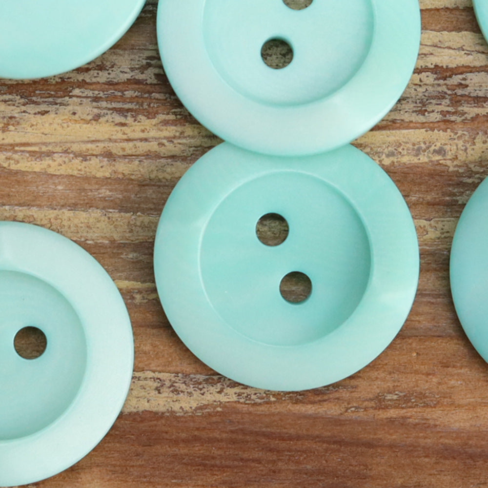 Sky blue irregular corozo 2-hole buttons, close-up of fronts and holes
