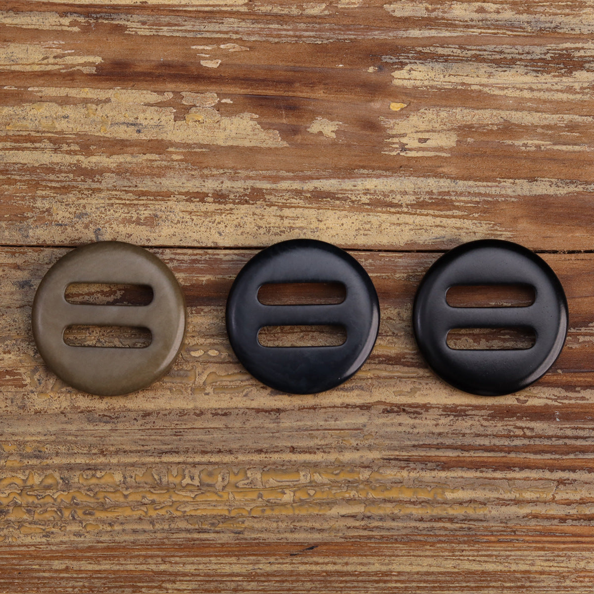 Corozo-style oblong-hole buttons in taupe/khaki, navy, and black; each has two slots