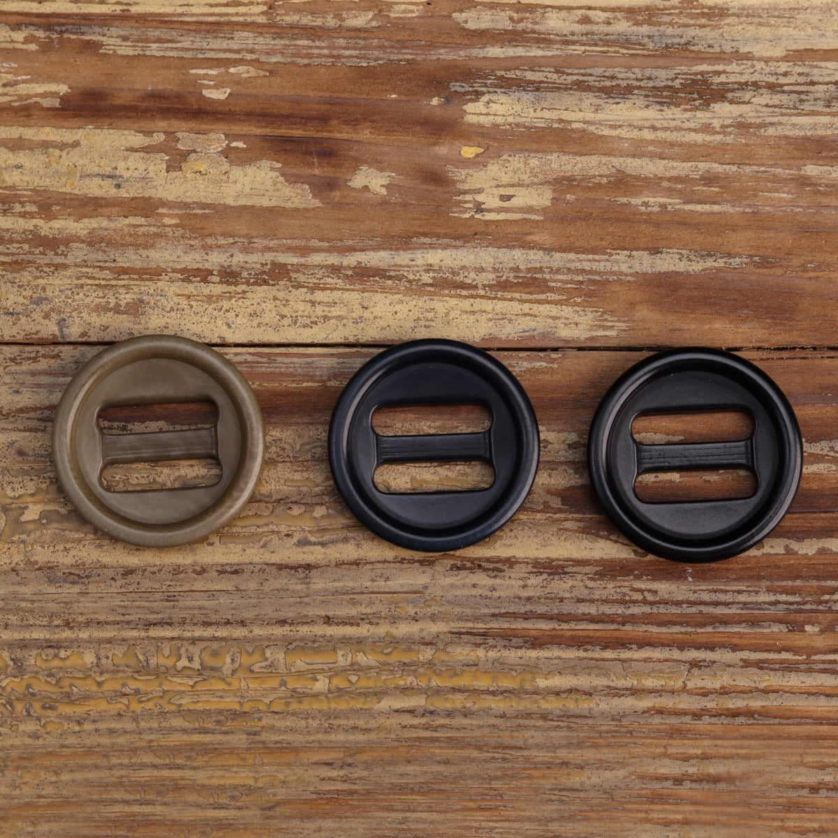 Three corozo-style oblong-hole buttons: khaki, dark navy, black; each shows two slots