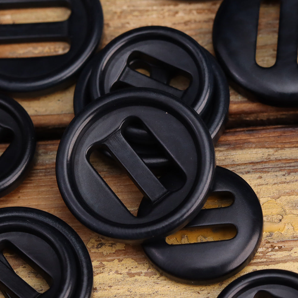 Close-up of dark gray/black corozo-style oblong-hole button with two angled slots