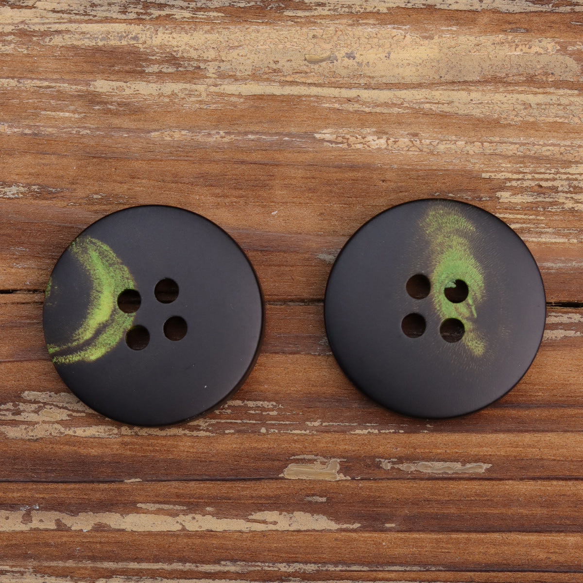 Two dark 4-hole buttons with green floral print, larger and smaller pair.