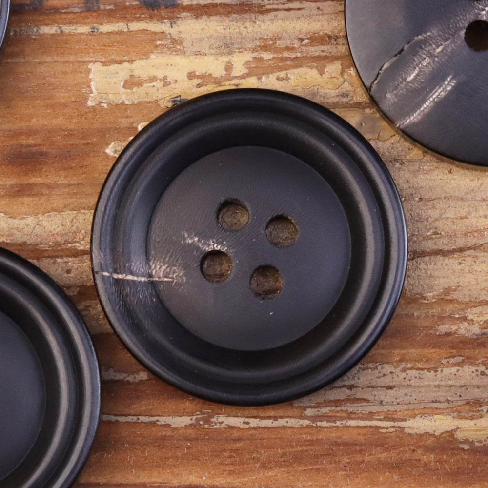 Close-up of a 15-25mm matte double-circle button with four holes, dark horn-look