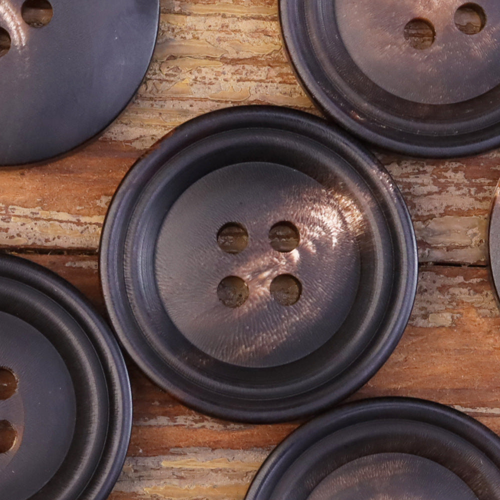 Matte 15-25mm double-circle horn-look button showing four holes and subtle grain
