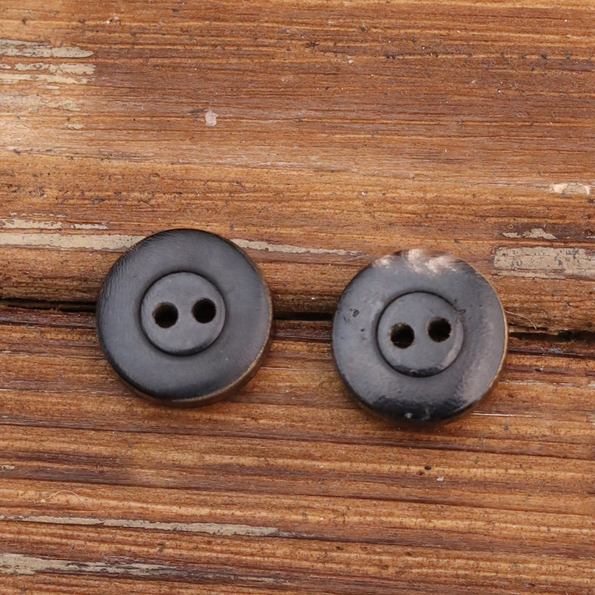 Two-hole horn buttons, charcoal-gray tone with two holes, round front view