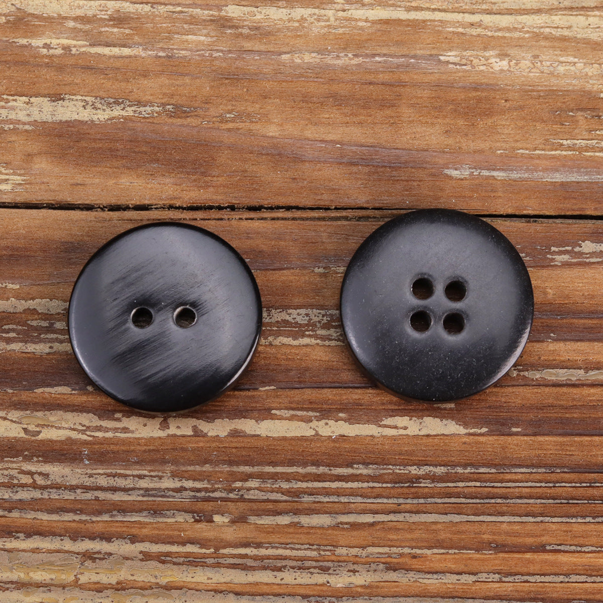 Black flat irregular horn-look buttons, one 2-hole and one 4-hole