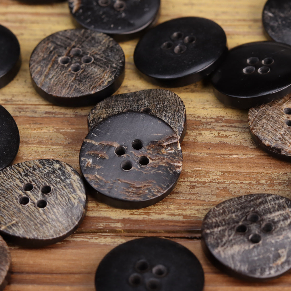 Rustic black textured horn-look buttons laid out, mixed 2-hole and 4-hole styles