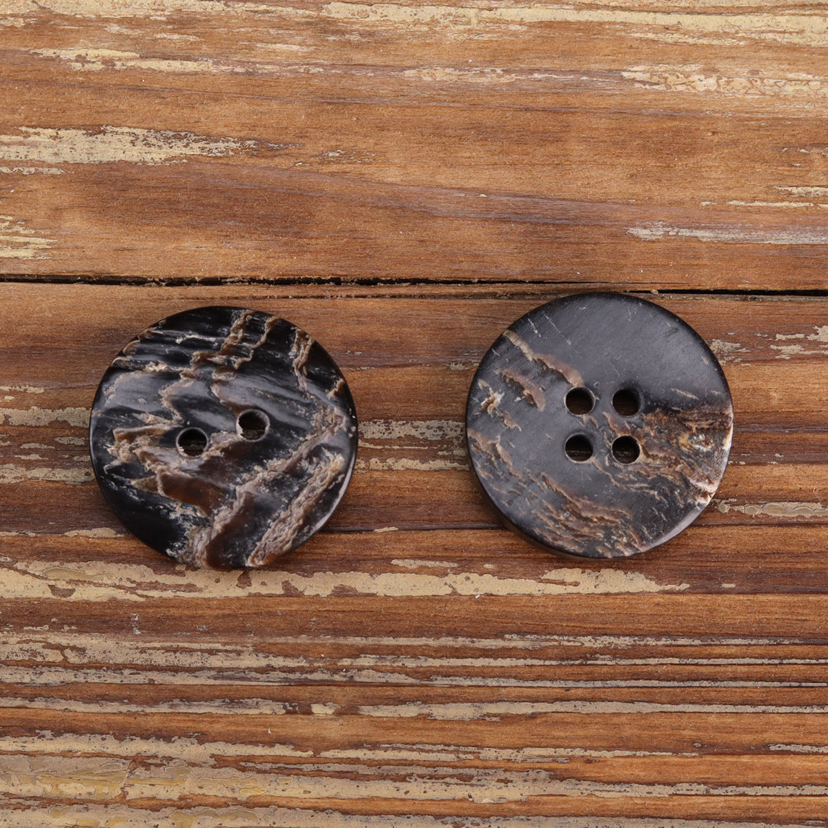 Pair of black irregular textured horn-look buttons, mixed 2-hole and 4-hole