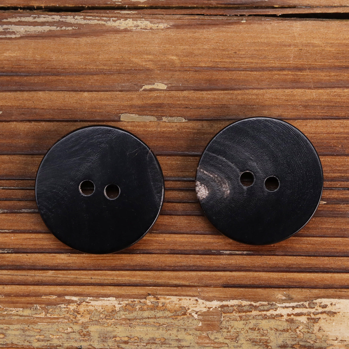 Two-hole buffalo horn button, black with silver-gray accents, front view pair