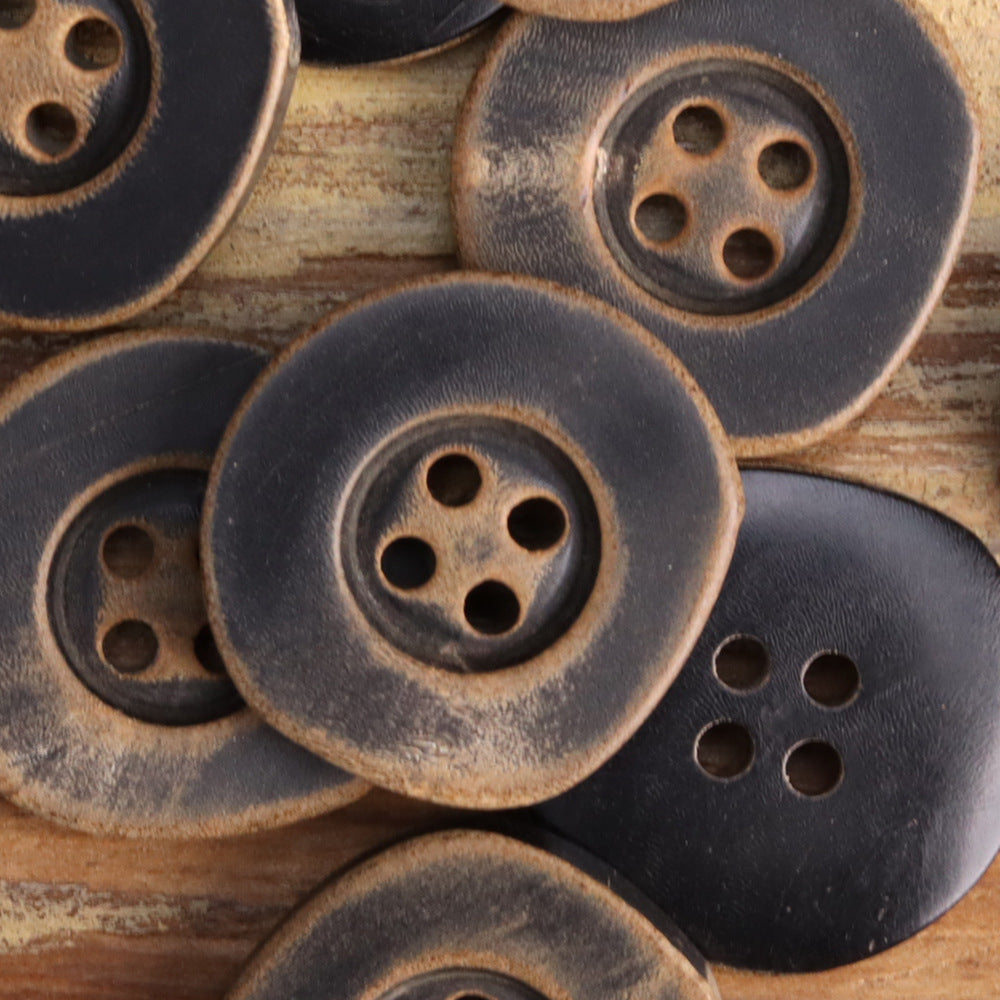 Close-up of irregular horn buttons with four holes, burnished black and coffee colors