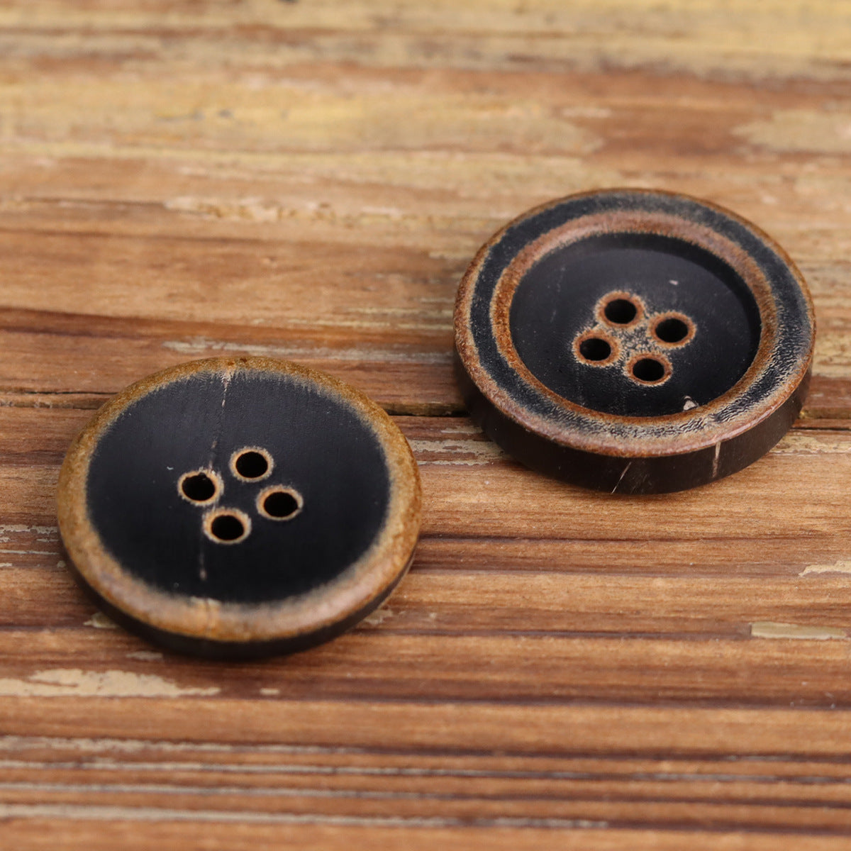 Vintage black horn button with rounded rim detail; four-hole face, slight wear