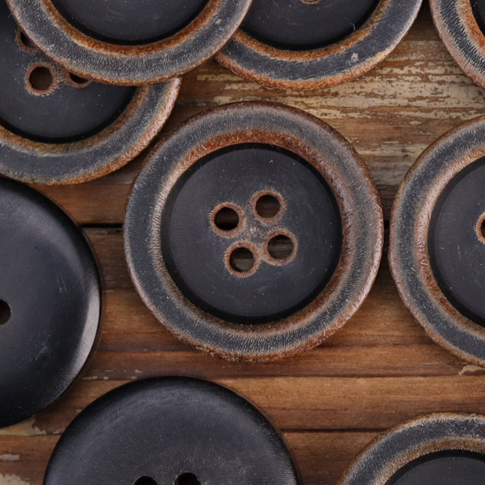 Black four-hole horn buttons with bowl-shaped profile and textured burnished edge