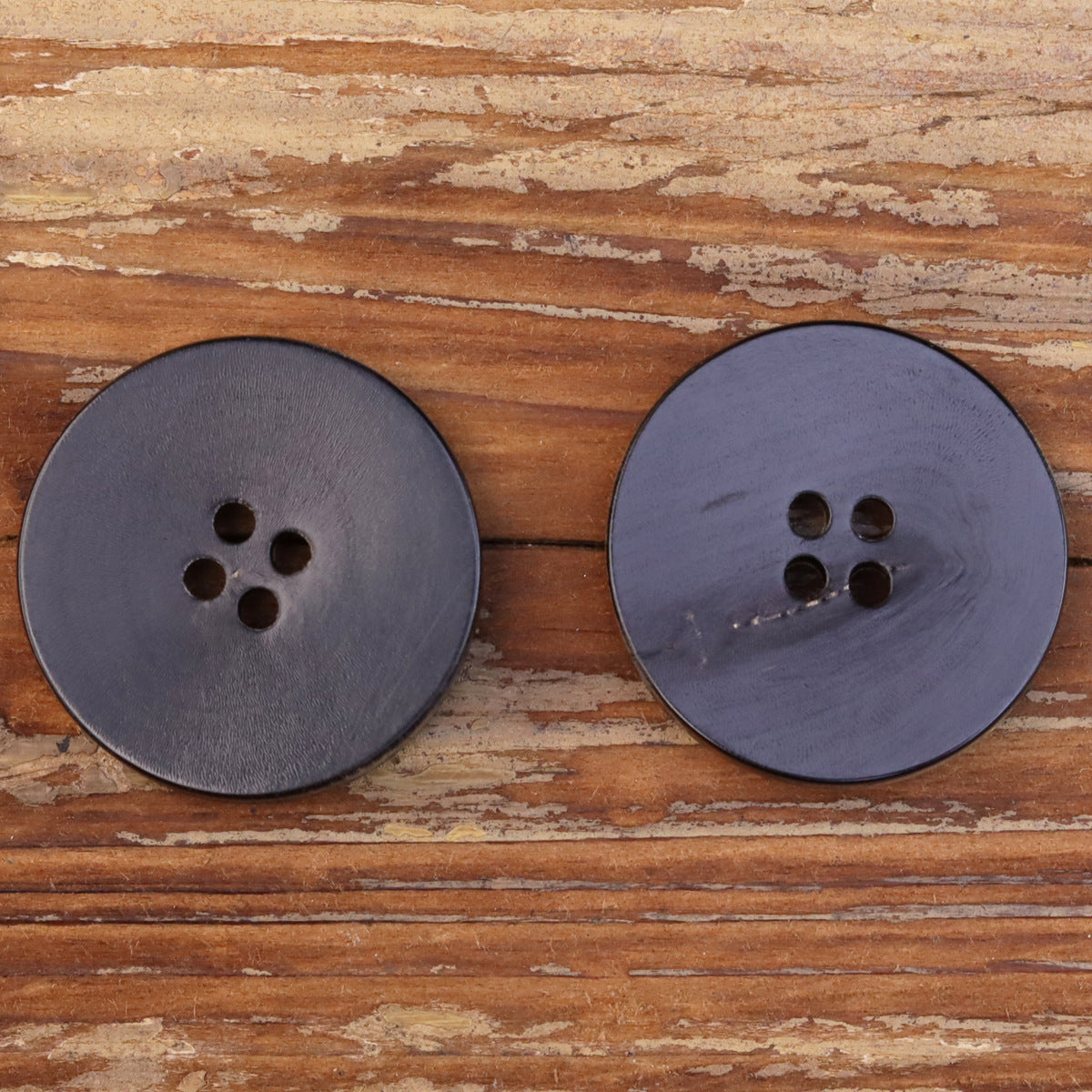 Pair of dark burned-horn four-hole buttons with bronze outer edge
