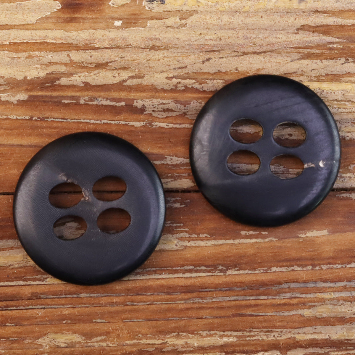 Black 4-hole horn-style buttons, two front views with four large holes