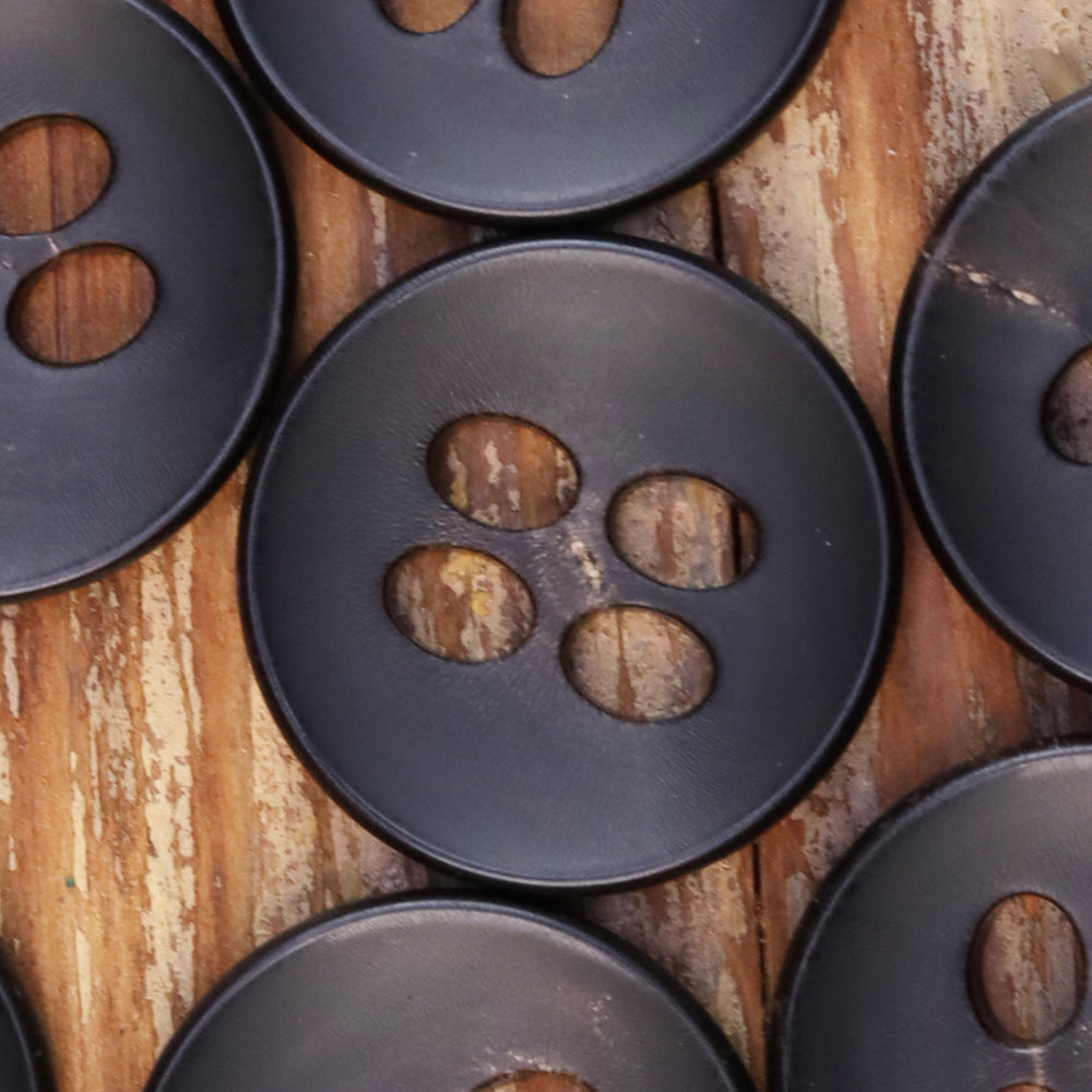 Set of black round 4-hole buttons, close-up of four large eyelet holes