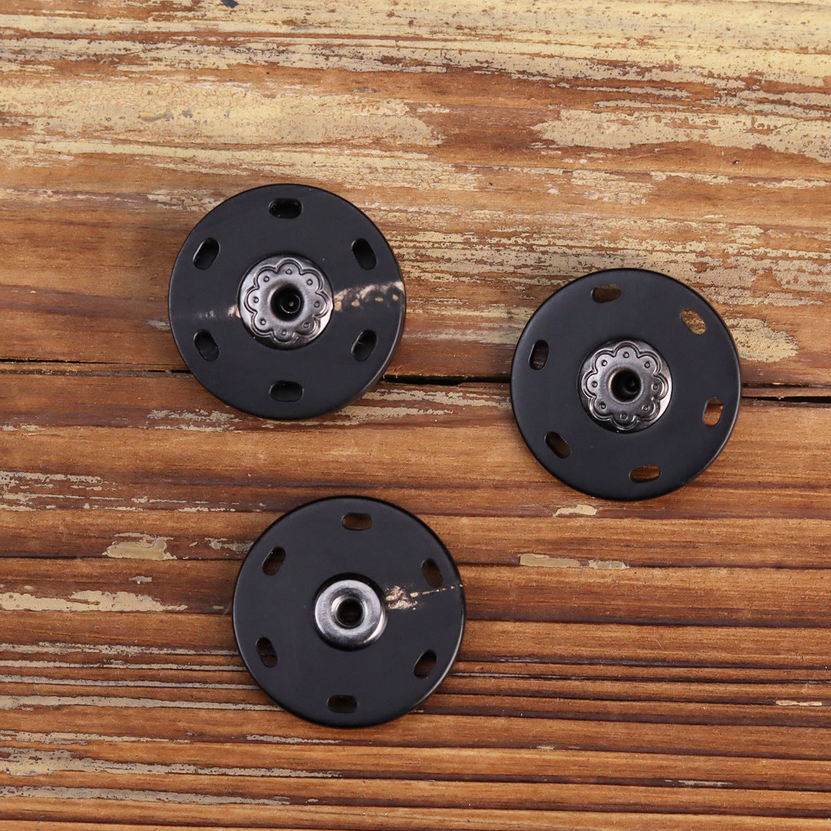 Drei schwarze Druckknöpfe mit Zier-Rosette und mittlerem Metallknopf