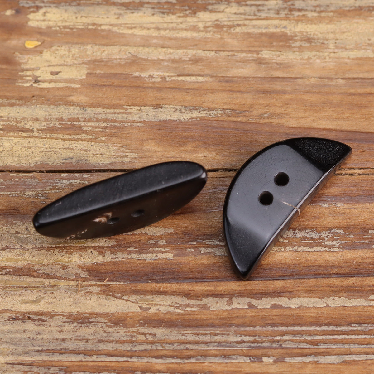 Black horn buttons with triangular half-moon design and round holes