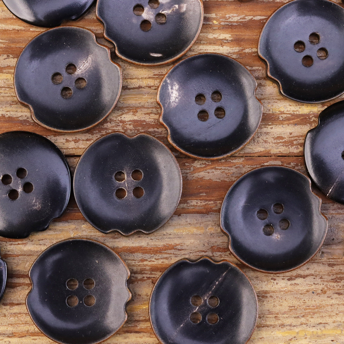 Small-to-medium dark irregular horn-look buttons showing different 4-hole layouts