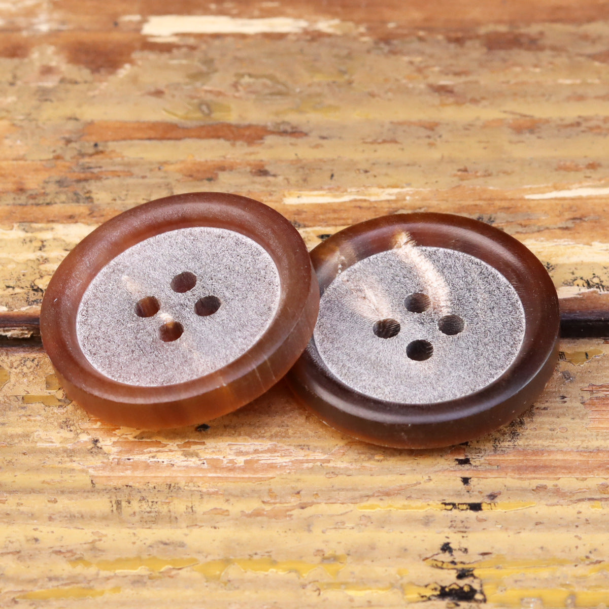 Pair of light coffee horn buttons, matte center, round four-hole pattern