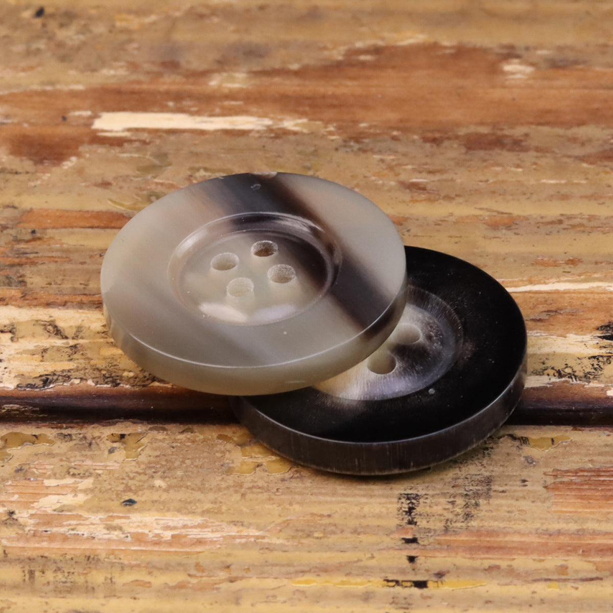 Two wide-edged horn-look buttons, 2pcs: beige and black, angled 4-hole fronts