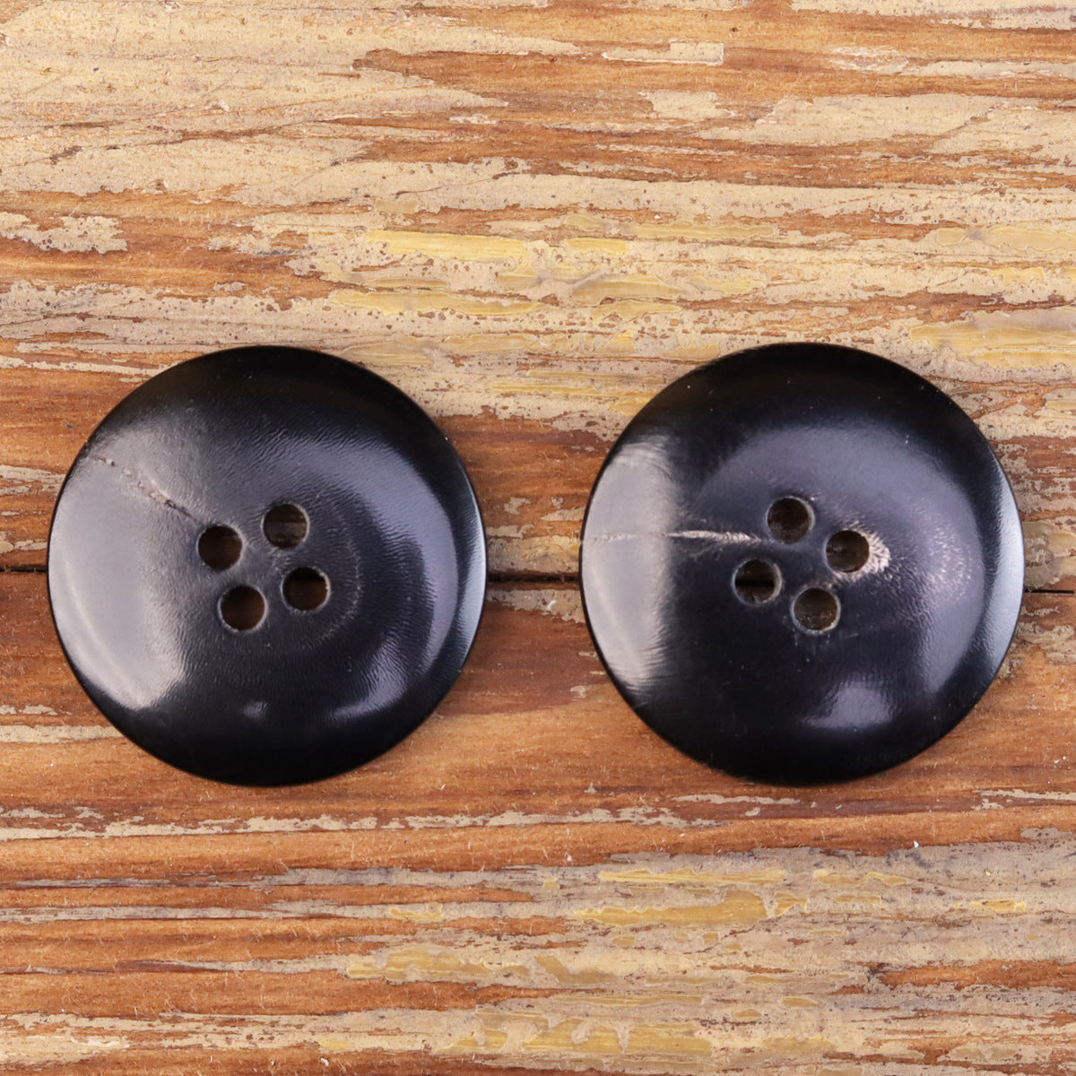 Two dark 4-hole jacket horn buttons, flat grooved edge detail, no yellow outline visible.