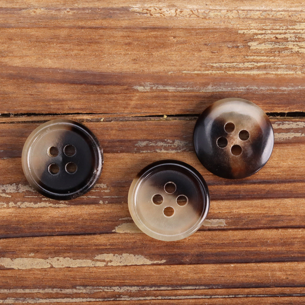 Round 4-hole shirt buttons in light and dark horn tones, side view