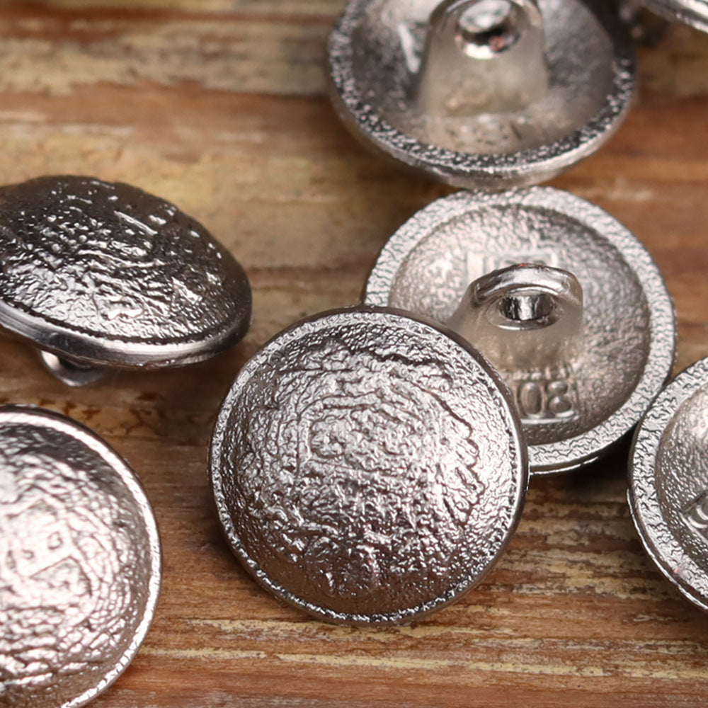 Nahaufnahme: matt-silberne Vintage-Metallknöpfe, Vorderseite mit Prägung und Öse