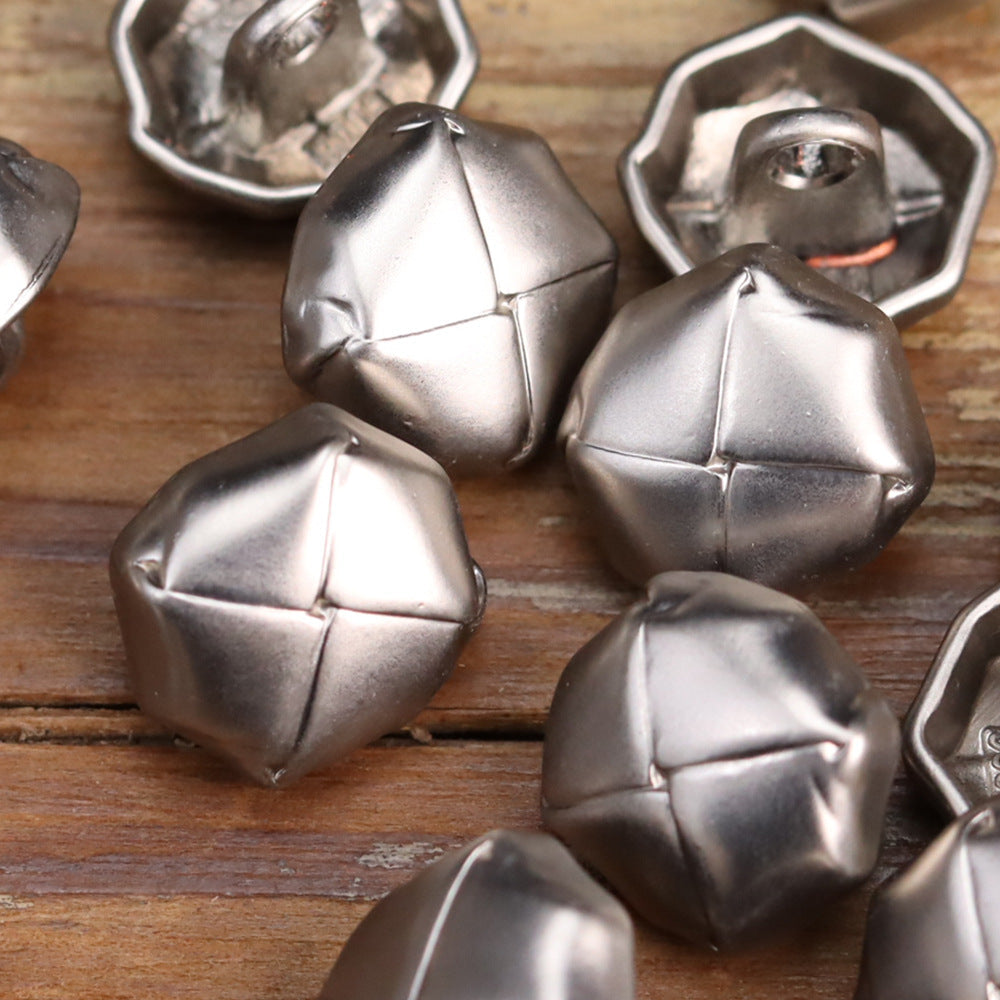 Close-up of distressed metal buttons with stitched cross lines; mostly silver tone