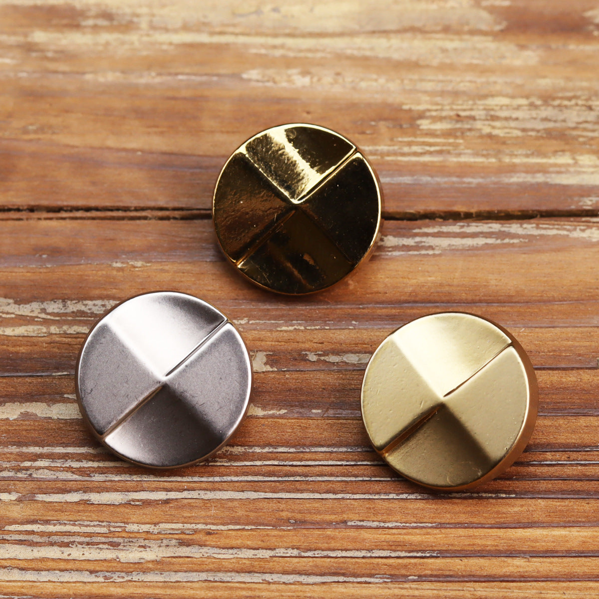 Shiny gold metal button with four-panel cross design