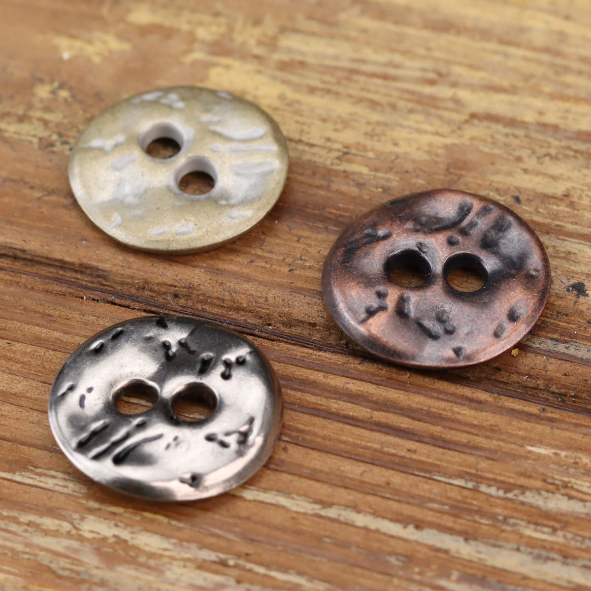Two-hole metal buttons, irregular textured face in antique silver and red bronze