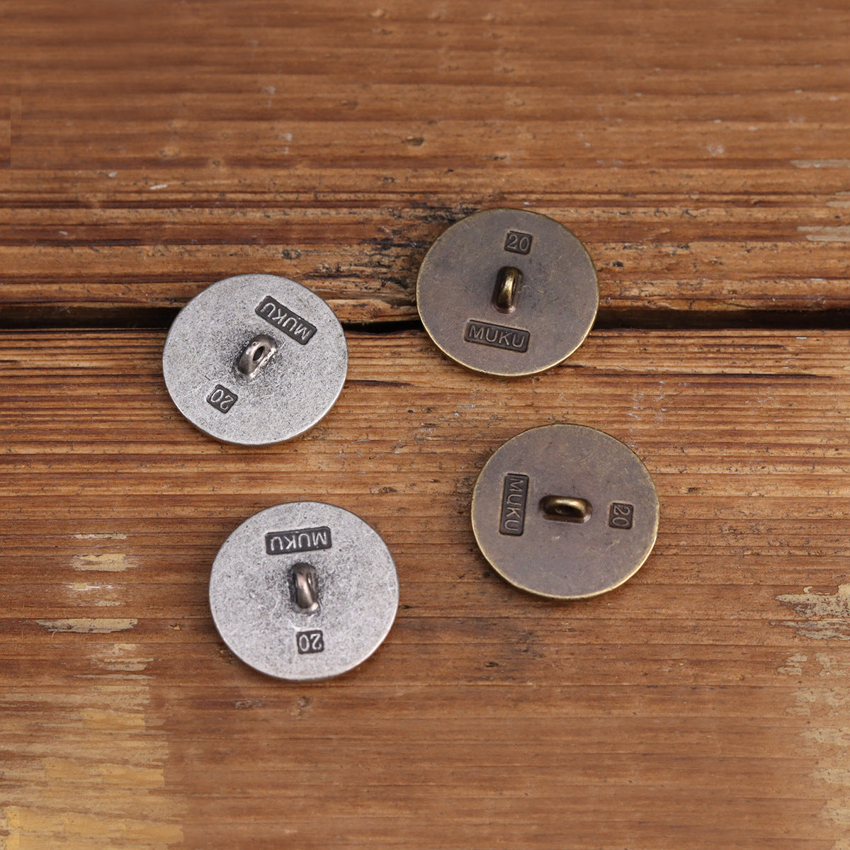 Back of metal sew-on buttons, engraved “20” and “MUKU”, two-hole hand-sewn style