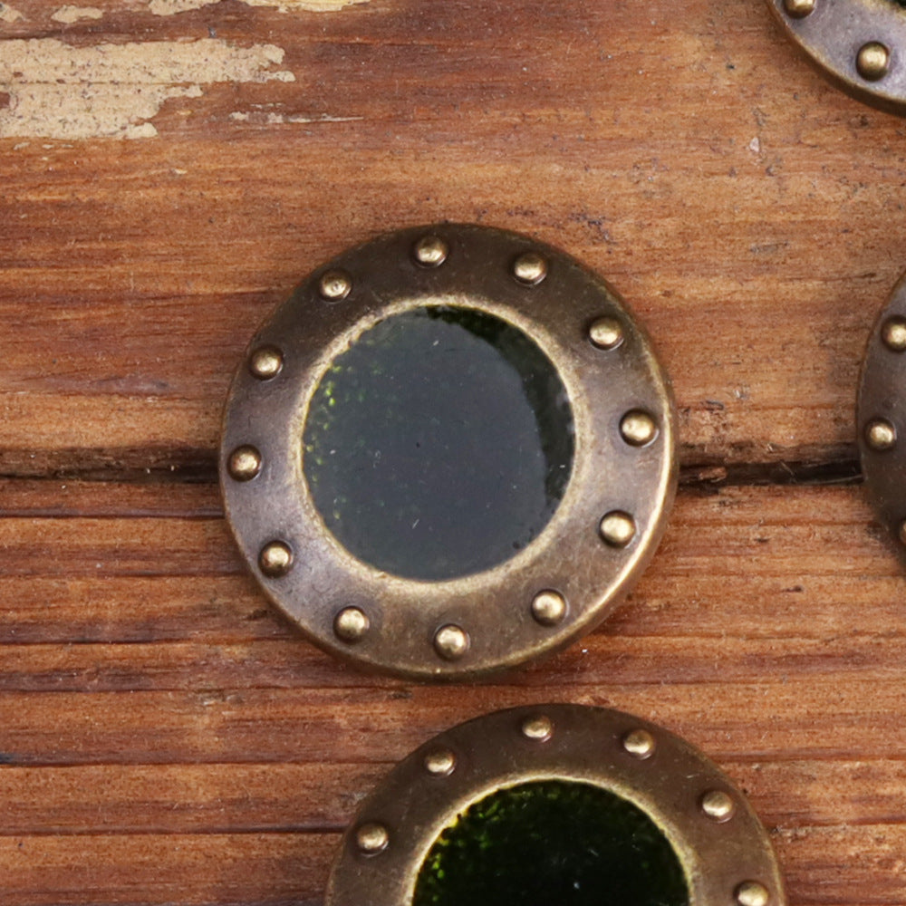 Round metal sew-on button with dark center and gold-tone stud rim, vintage patina