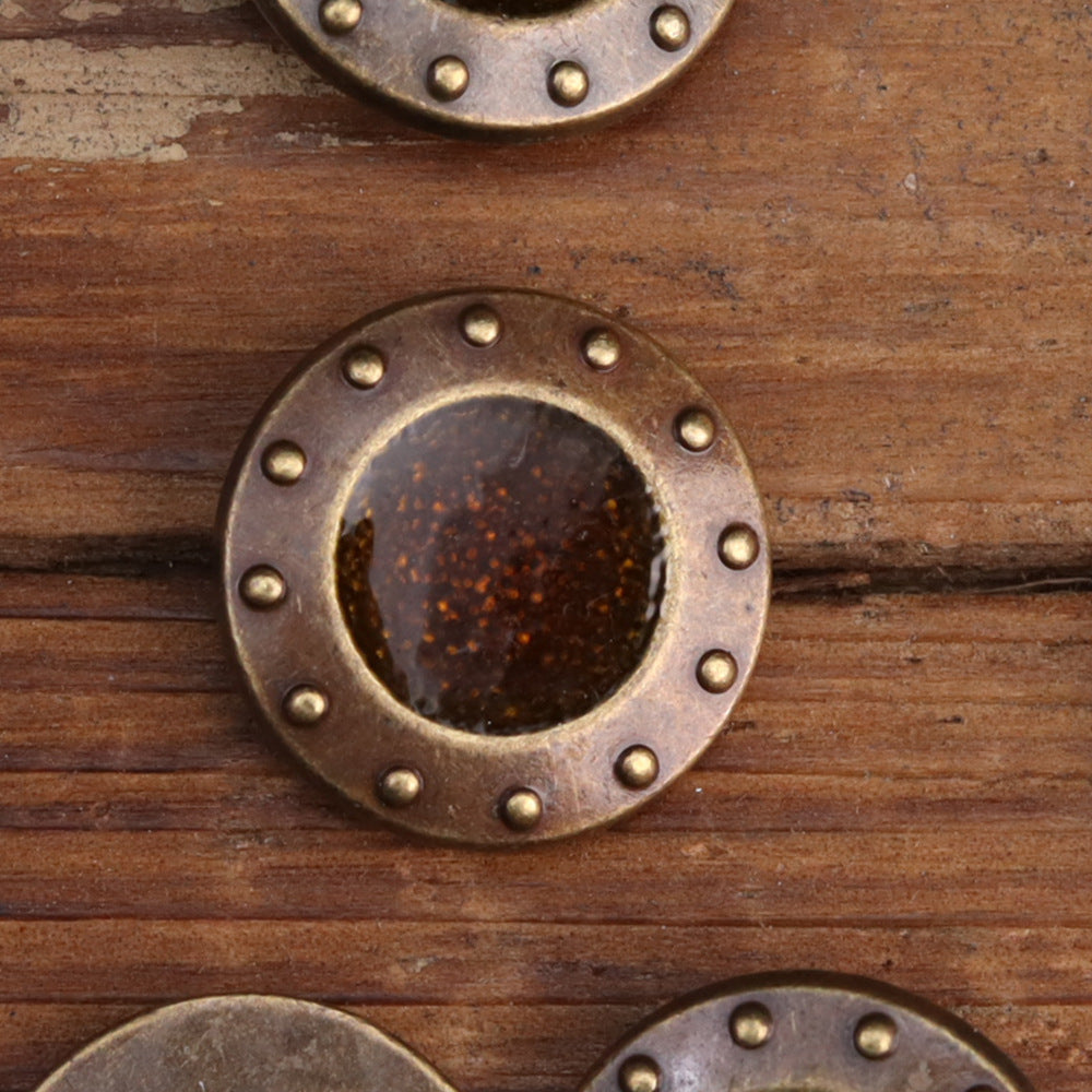 Metal sew-on button with brown glitter center and studded rim; flat face view