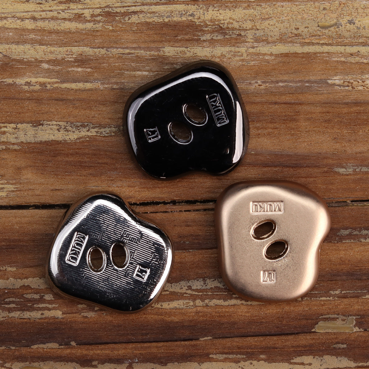 Gun black and silver irregular two-hole metal buttons on wood