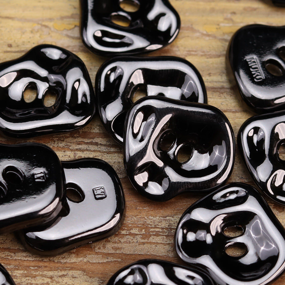 Irregular black and silver shiny two-hole metal buttons, close-up