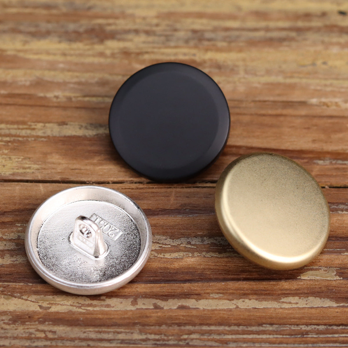 Matte flat-shank metal buttons: black, silver, and gold front faces