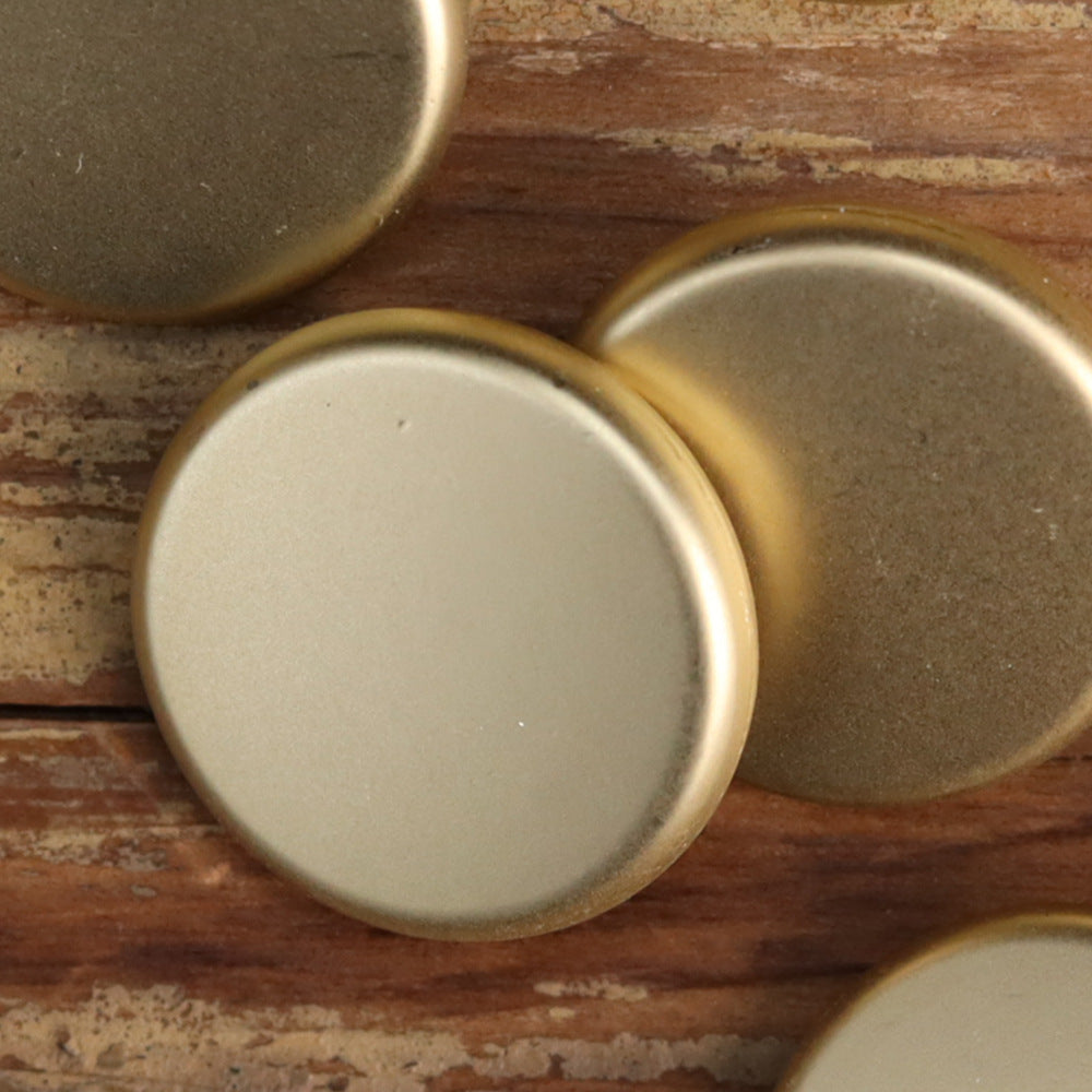 Matte flat-shank metal buttons close-up: gold and silver round faces