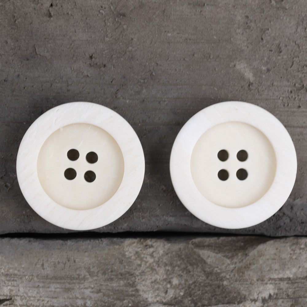 Pair of off-white wide-edge 4-hole buttons with dark shank holes